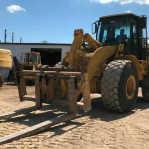 Angled view of Cat 966H loader equipped with loading forks.